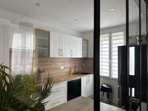 a kitchen with white cabinets and a black refrigerator at Beau Séjour in Épernay