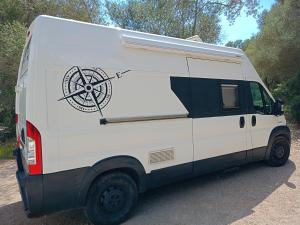 Una furgoneta blanca con una rueda en el costado. en Furgoneta Camper Gran Volumen, en Palma de Mallorca