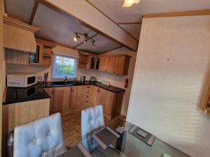 uma cozinha com armários de madeira e cadeiras azuis em Great Caravan With Spacious Decking Southview Holiday Park, Skegness Ref 33035v em Skegness