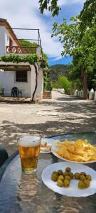 een tafel met twee borden eten en een glas bier bij Cortijo Balzain in La Zubia