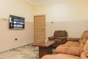 a living room with two chairs and a tv at J's Place Hotel in Abuja