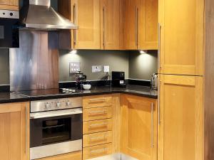 cocina con armarios de madera y horno con fogones en Marlin Apartments Commercial Road - Limehouse, en Londres