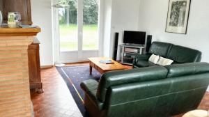 een woonkamer met een groene leren bank en een tafel bij Maison de 4 chambres avec jardin clos et wifi a Pontorson in Pontorson