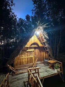 a thatch roofed hut with a table and chairs at FARMSTAY HOÀNG HÔN in Xóm Mũi