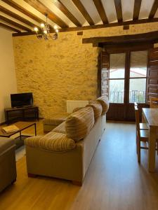 sala de estar con sofá y pared de piedra en La Casona de 1717, en El Burgo de Osma