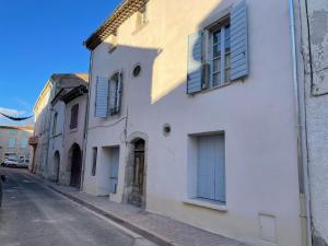 ein weißes Gebäude mit blauen Rollläden auf einer Straße in der Unterkunft Studio in the heart of historical house in Villeneuve-lès-Béziers