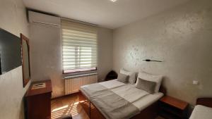 een kleine slaapkamer met een bed en een raam bij Dukat Apartmani-Studio in Vrnjačka Banja