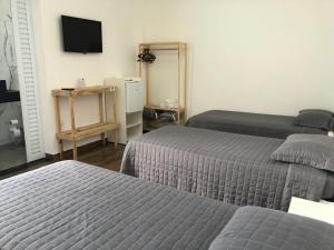 1 dormitorio con 2 camas y TV en la pared en Hospedaria Colinas, en Indaiatuba