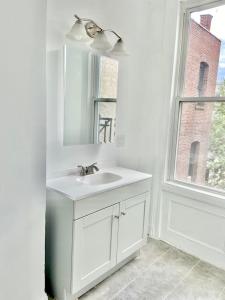 Baño blanco con lavabo y espejo en 408-Newly Renovated 3 Bed 2 Bath Apartment, en Hoboken