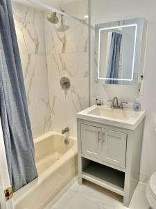 a bathroom with a sink and a tub and a mirror at 310-Entire House in Uptown Hoboken in Hoboken