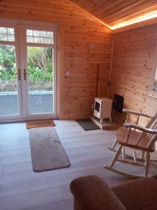 a living room with wooden walls and a room with a tv at Kilcavan Chalet in Gorey