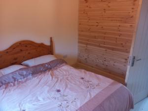 a bedroom with a bed with a wooden wall at Kilcavan Chalet in Gorey