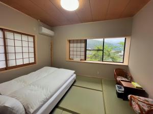 a bedroom with a bed and two windows at 湯布院我楽珍民泊Yufuin Garakuchin in Yufuin