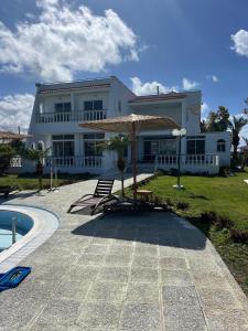 a large white house with an umbrella and a pool at Ayit Hotel in Theologos