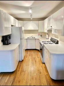 een witte keuken met witte apparatuur en houten vloeren bij 330- Unique Uptown W Lofted Bedrooms in Hoboken