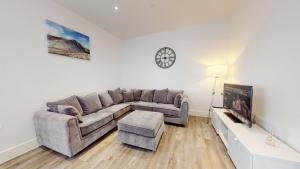 a living room with a couch and a clock on the wall at Spacious three bedroom apartment with Valley views in Abertillery