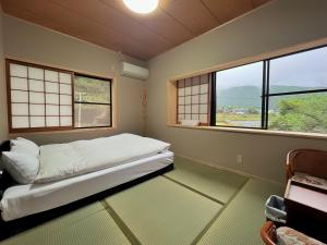 pokój z łóżkiem w pokoju z oknami w obiekcie 湯布院我楽珍民泊Yufuin Garakuchin w mieście Yufu
