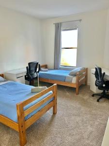 1 Schlafzimmer mit 2 Betten, 2 Stühlen und einem Fenster in der Unterkunft 0123-Spacious Apartment in the Heart of Hoboken in Hoboken