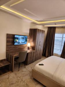 Le Masik Hotel في Ilora: غرفة فندقية فيها سرير ومكتب وتلفزيون