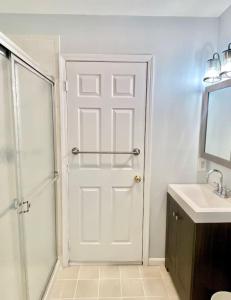 La salle de bains est pourvue d'une douche et d'une porte blanche. dans l'établissement 203-Vivid and Charming 2 bed 2 bath With Balcony, à Hoboken
