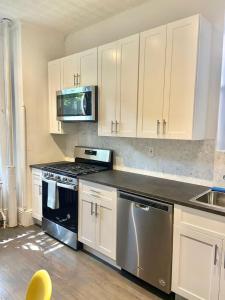 eine Küche mit Küchengeräten aus Edelstahl und weißen Schränken in der Unterkunft 301-Two Bedroom Apartment in Hoboken in Hoboken