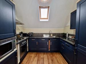 a kitchen with navy blue cabinets and a window at Chic Luxury Serviced Apartment next to City Centre with Free Parking - Contractors & Relocators in Coventry