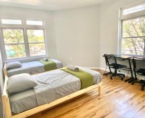 a bedroom with two beds and a table and windows at 202-Renovated Modern 2 Bed 2Bath Hoboken Apartment in Hoboken