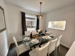 uma sala de jantar com uma mesa de vidro e cadeiras brancas em Spacious Family home in great location in Cardiff em Cardiff