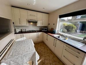a kitchen with a table and a sink and a window at Spacious Family home in great location in Cardiff in Cardiff