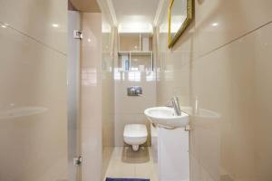 Baño blanco con lavabo y aseo en One bedroom apartment. en Ciudad del Cabo