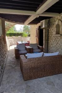 un patio al aire libre con sillas de mimbre y una mesa en La Cave de Pérès, en Ayguetinte
