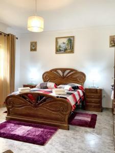 ein Schlafzimmer mit einem großen Holzbett mit lilafarbenen Teppichen in der Unterkunft 4 bedrooms house with city view enclosed garden and wifi at Corticada in Cortiçada