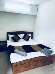 um quarto com uma cama de madeira com almofadas pretas e brancas em Tarun Residency em Saharanpur