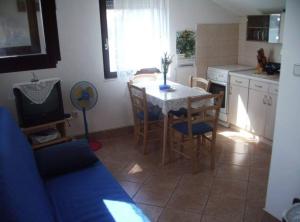 een keuken met een tafel en stoelen en een televisie bij Apartment Mirjana in Prvić Luka
