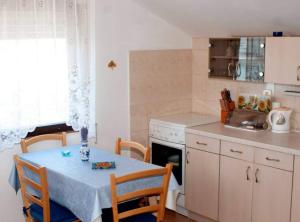 een keuken met een tafel en stoelen, een tafel en een fornuis bij Apartment Mirjana in Prvić Luka