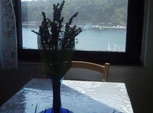 eine blaue Vase auf einem Tisch mit einem Fenster in der Unterkunft Apartment Mirjana in Prvić Luka