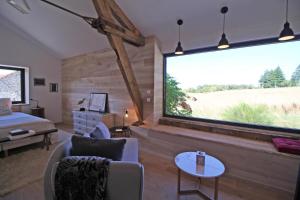 een slaapkamer met een groot raam met een bed en een tafel bij Kernad in Bersac-sur-Rivalier
