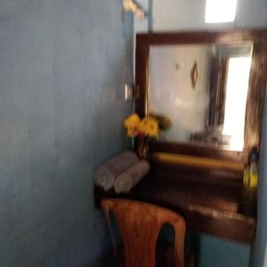 een bureau met een spiegel en een vaas met bloemen bij REVESTON HOLIDAYS in Matale