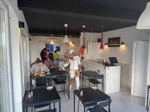 a person standing in a restaurant with people sitting at tables at Residence Spa Apartments DUB in Kotor