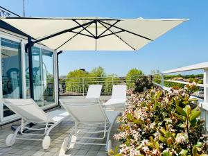 eine Terrasse mit weißen Stühlen und einem Sonnenschirm in der Unterkunft Hotel Miramare - SPA & Suites - Breakfast & Brunch Until 13-00 in Cervia