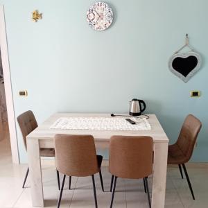 a white table with chairs and a clock on the wall at Casa Irene in Catania