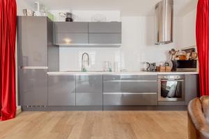 uma cozinha com electrodomésticos de aço inoxidável e cortinas vermelhas em Appartement spacieux à 15 minutes du jet d'eau em Genebra