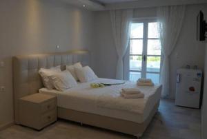 ein weißes Schlafzimmer mit einem Bett, auf dem Handtücher liegen in der Unterkunft Hotel Sagterra in Naxos Chora