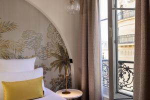 a bedroom with a bed with a yellow pillow and a window at Hotel Elysées Bassano in Paris