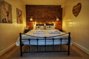 a bedroom with a bed with a wooden wall at 1 Bed Cottage - Hot Tub Pool Wifi Pets in Holsworthy
