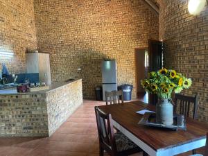 een eetkamer met een tafel met een vaas met bloemen erop bij Soetgeluk Farm Cottage in Hekpoort