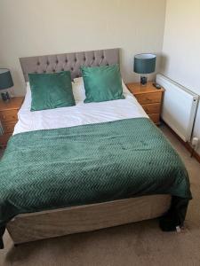 a bed with two green pillows on top of it at Impala Guest House in Wick