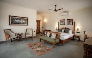 ein Schlafzimmer mit einem Bett, Stühlen und einem Tisch in der Unterkunft Aloof Jungle Lodge in Ghānerao