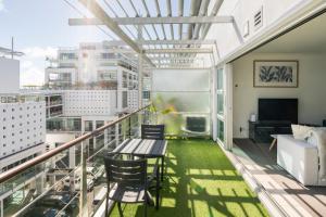 een balkon met een tafel en stoelen en een bank bij Welcome To Your Secluded Luxury Abode in Auckland