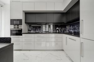 a kitchen with white cabinets and black appliances at Luksusowy Apartament z 3 Sypialniami, Klimatyzacją, Parkingiem i Biurkiem we Wrocławiu by Renters Prestige in Wrocław